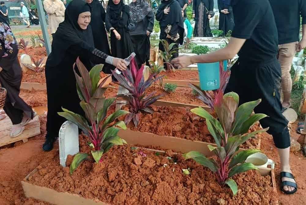 Ogy menyiram air pada kubur adiknya.