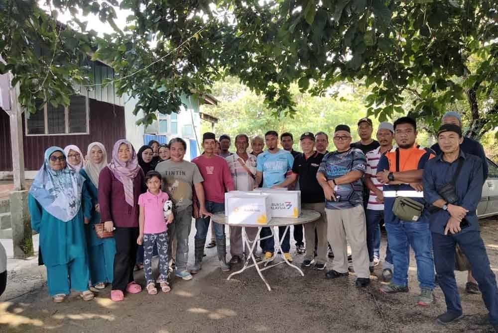 Muhammad Nasir (empat, kanan) bergambar bersama mangsa banjir yang menerima bantuan.