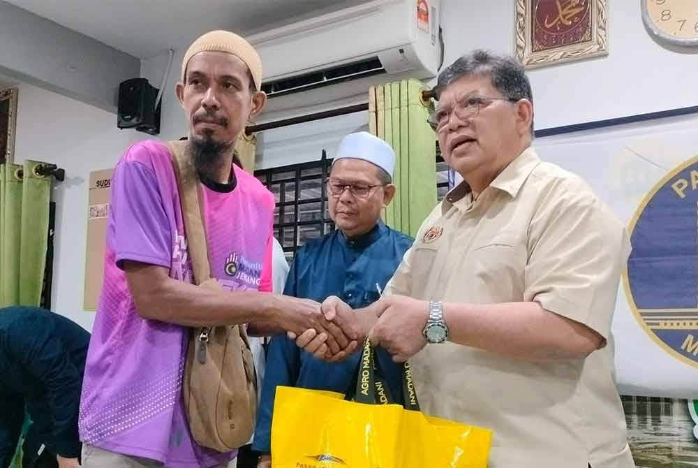 Johari (kanan) menyampaikan sumbangan kepada salah seorang mangsa banjir di Masjid Safuan Pekan Jeniang pada Selasa.