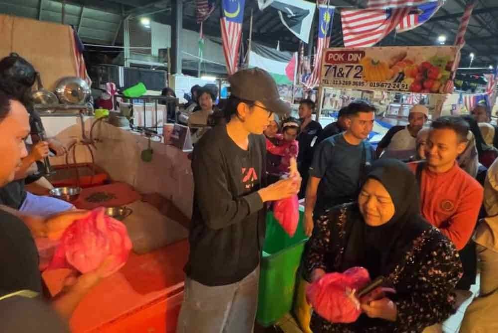 Usahawan, Muhammad Syahmie Rizuan Mohd Yusof atau lebih dikenali sebagai Ervan Rizuan (tengah) mengagihkan ayam percuma kepada orang ramai.