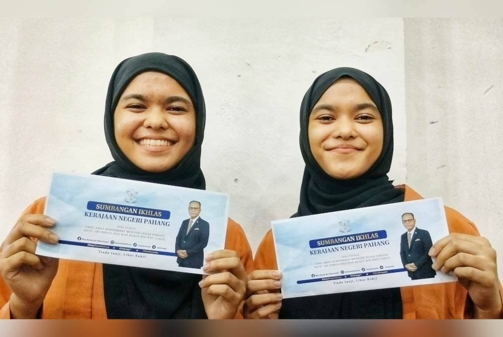Nurulhudaa (kiri) dan Nuruljannah ceria dengan insentif yang diterima daripada kerajaan negeri.