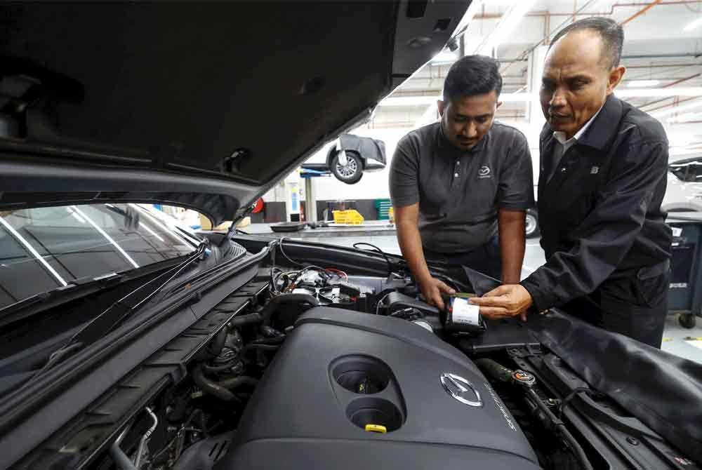 Shamsuddin (kanan) yang juga Pengerusi Kluster Pendidikan dan latihan Teknikal dan Vokasional (TVET) bersama Juruteknik Automotif Bermaz Auto Berhad, Muhammad Syabil Syahmi Norazam, 24, melakukan pemeriksaan salah sebuah kereta di Bermaz Motor Trading Sdn Bhd, baru-baru ini. Foto Bernama