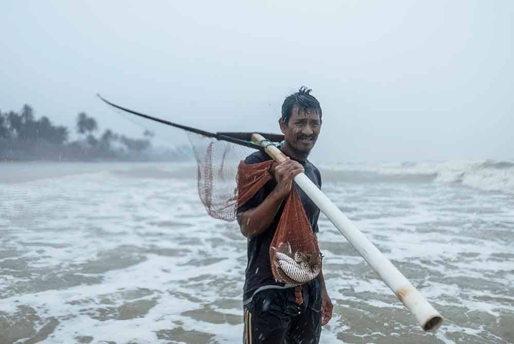 Nelayan di Kampung Pangkalan Baru Suhairan Mohamed, 42, mengharungi ombak besar yang membadai pesisir pantai untuk menyauk ikan belanak. Foto Bernama