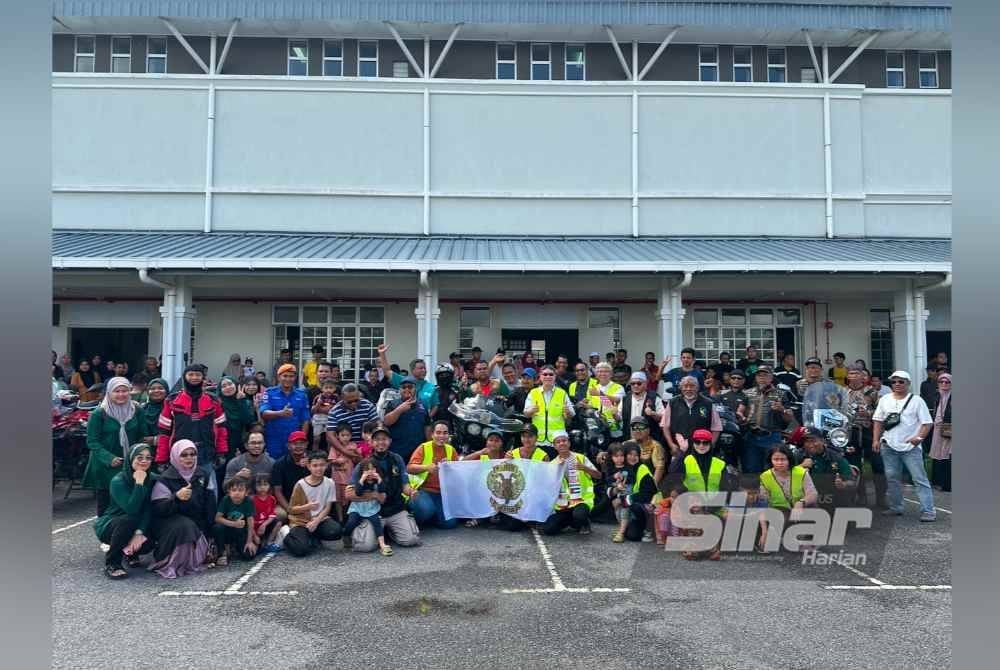 Pemilik motosikal berkuasa tinggi bergambar bersama-sama mangsa banjir.