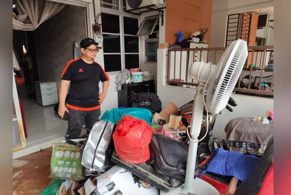Shamsudin menunjukkan perkakasan rumah yang rosak selepas kawasan perumahan dilimpahi air kesan benteng kolam takungan pecah.