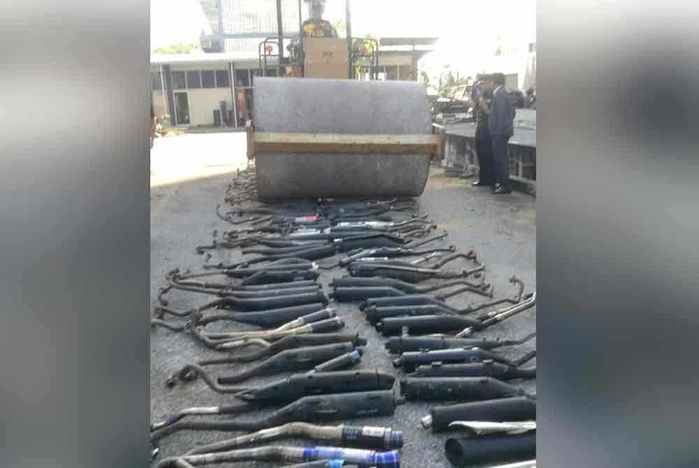 Sebahagian ekzos motosikal yang dirampas dilupuskan menggunakan penggelek jalan pada Selasa.