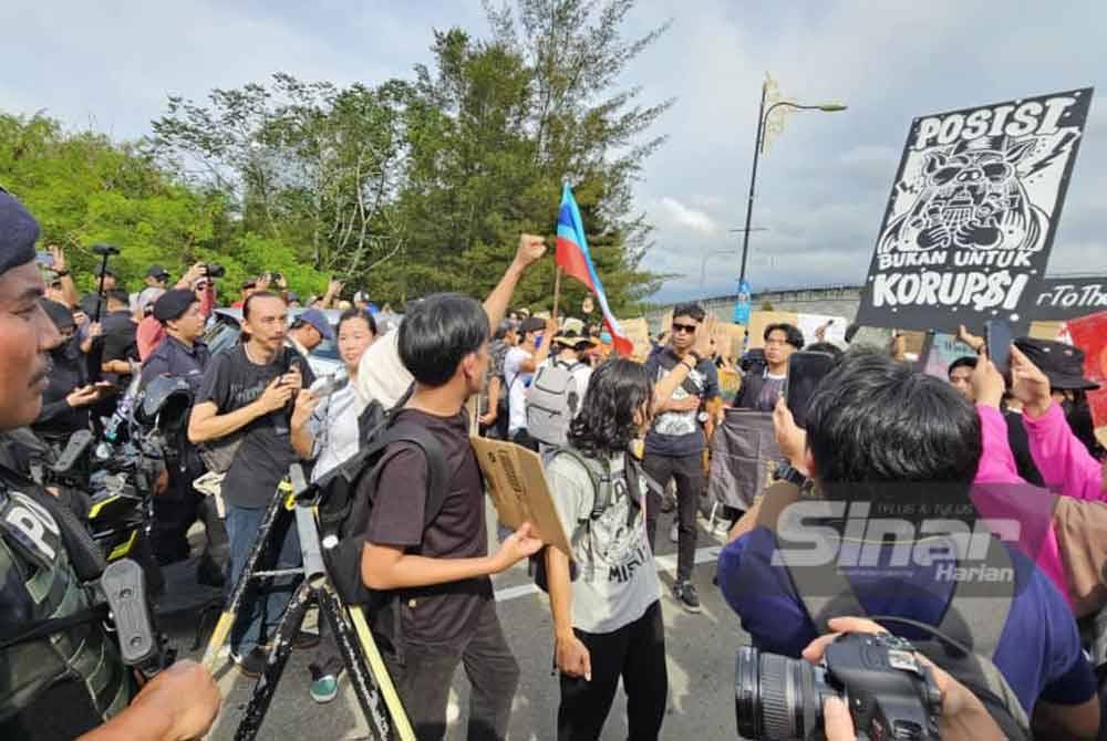 Peserta berarak sambil membawa plakad dan sepanduk ke arah Menara Kinabalu.