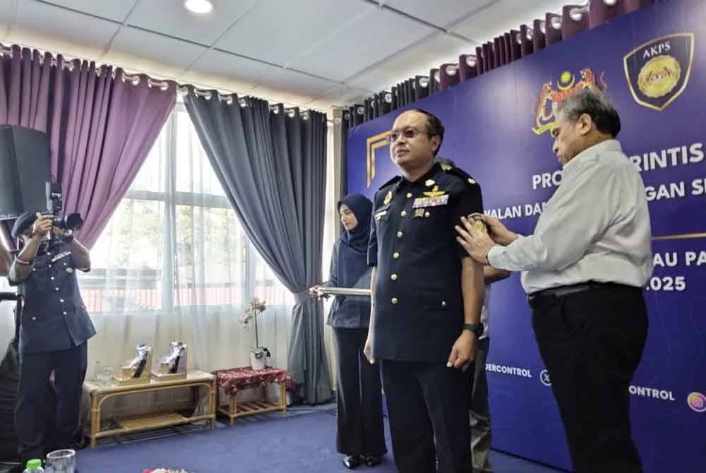 Shamsul Azri (kanan) memakaikan logo AKPS kepada kakitangan agensi itu Program Rintis AKPS di Kompleks ICQS Rantau Panjang pada Rabu.