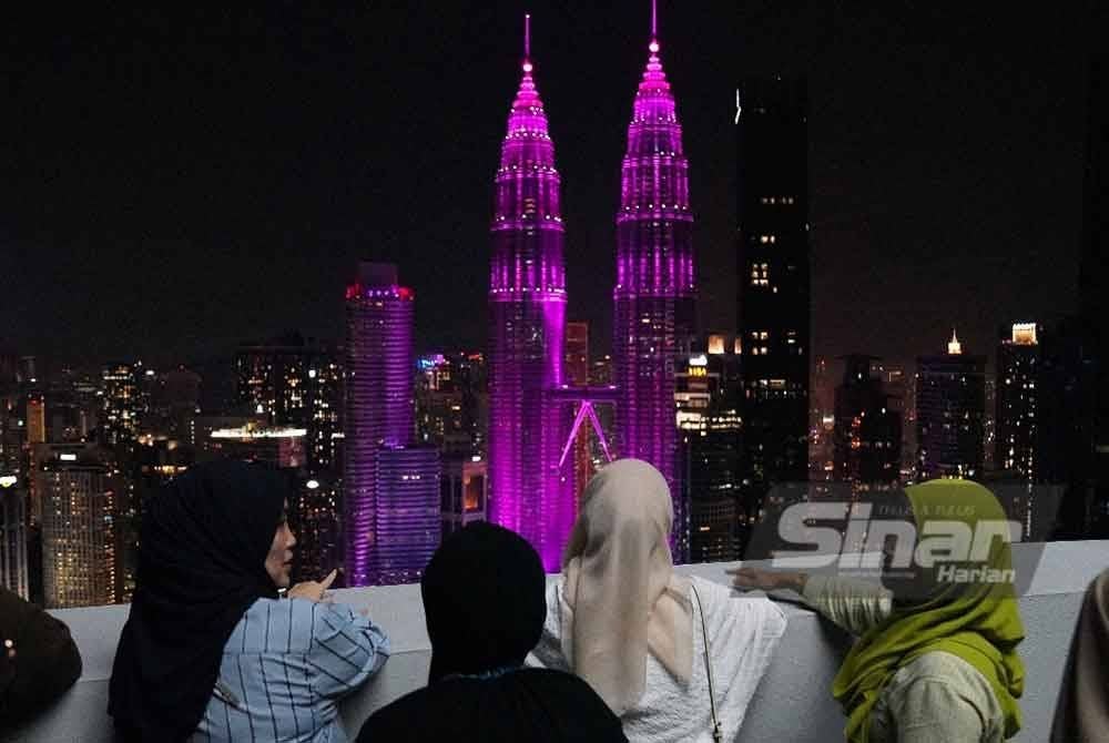 Kakitangan dah ahli keluarga melihat permandangan ibu kota Kuala Lumpur sebelum pertunjukan bunga api sempena ambang Tahun Baharu 2025 yang dirakam dari Tingkat 50, Menara Felda, Kuala Lumpur. FOTO SINAR HARIAN-ROSLI TALIB
