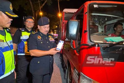 Muhammad Kifli (kanan) menunjukkan lesen digital milik pemandu lori yang diperiksa di Kota Bharu pada Selasa. FOTO SINAR HARIAN-ADILA SHARINNI WAHID.