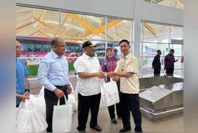 Muhammad Sanusi (tiga dari kiri) menyerahkan beg cenderamata kepada pelancong Thailand yang melancong ke Kedah pada Rabu sempena Tahun Melawat Kedah 2025 di Kompleks ICQS Bukit Kayu Hitam.