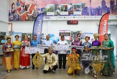 Muhammad Sanusi (lima dari kanan) bergambar bersama artis kebudayaan negeri Kedah yang turut menyambut pelancong di Kompleks ICQS Bukit Kayu Hitam pada Rabu.