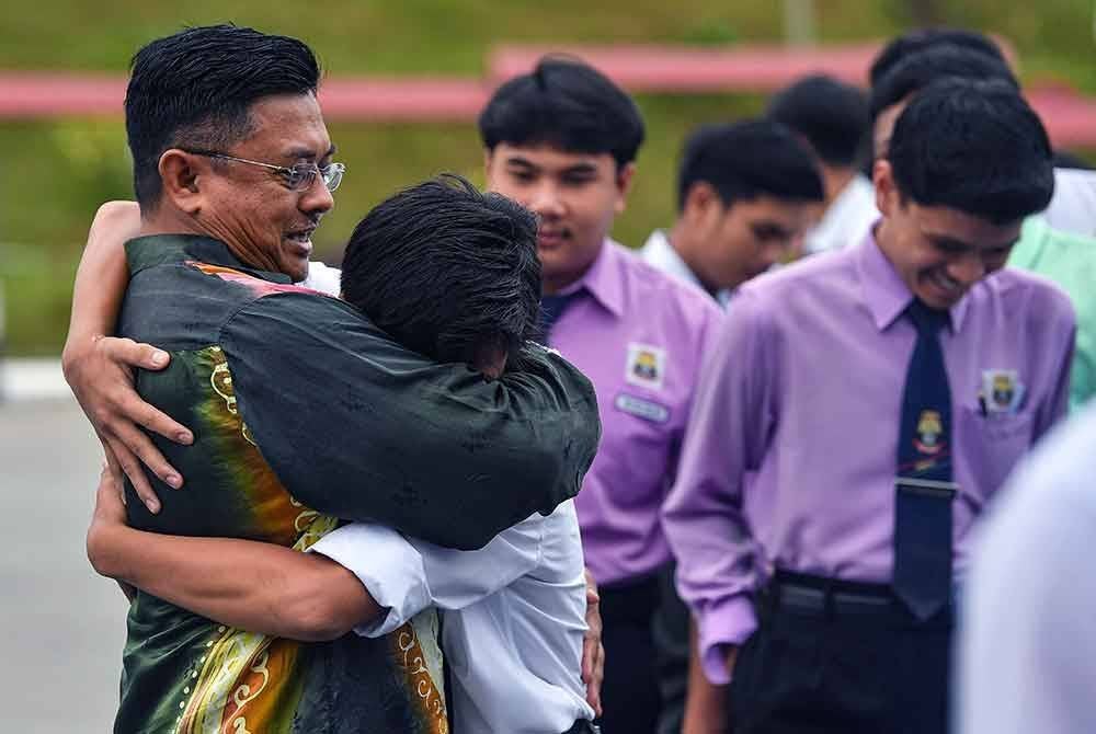 Pengetua SMK Undang Jelebu Muhamad Fadzli Hamid (kiri) memeluk calon Sijil Pelajaran Malaysia (SPM) untuk memberi semangat sebelum mereka memasuki dewan peperiksaan bagi mula menjawab Bahasa Melayu Kertas I pada hari pertama SPM 2024 di Sekolah Menengah Kebangsaan (SMK) Undang Jelebu, hari ini.