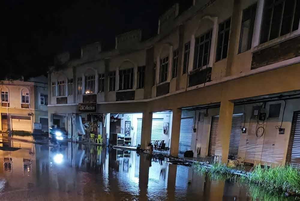 Air laut pasang melimpah dan bergenang di atas jalan pada waktu malam.