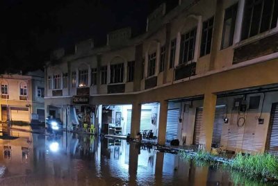Air laut pasang melimpah dan bergenang di atas jalan pada waktu malam.