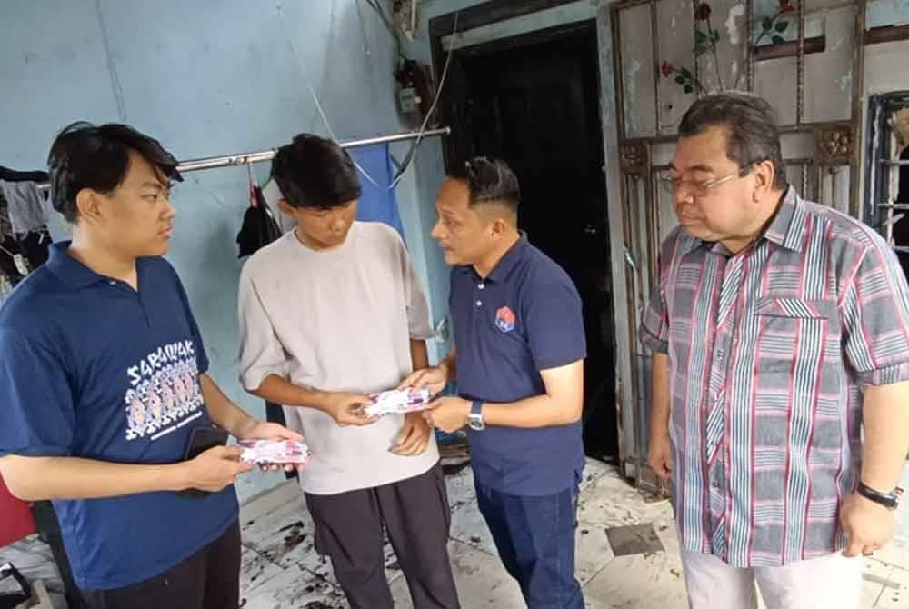 Aznan (dua dari kanan) menyampaikan sumbangan kepada dua beradik berkenaan.