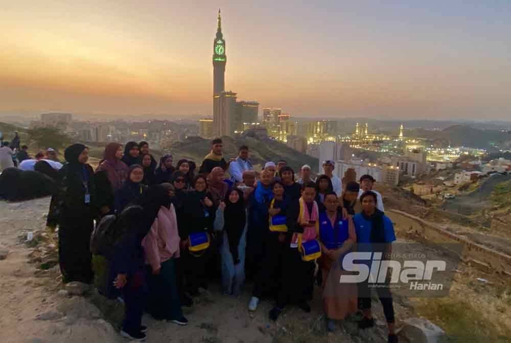 Peserta Program Umrah Percuma Anak Muda Jati Kelantan bergambar berlatar belakangkan keindahan Masjidil Haram di atas puncak bukit.