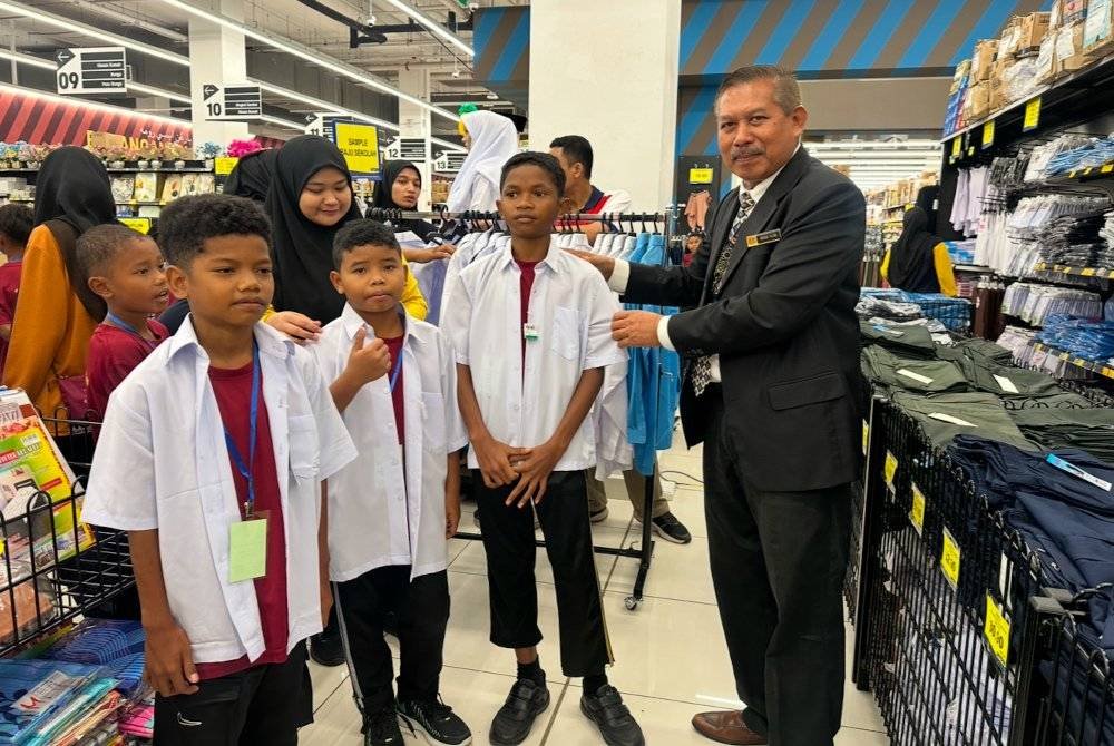 Mhd Nor (kanan) mencuba saiz baju kepada murid Orang Asli.