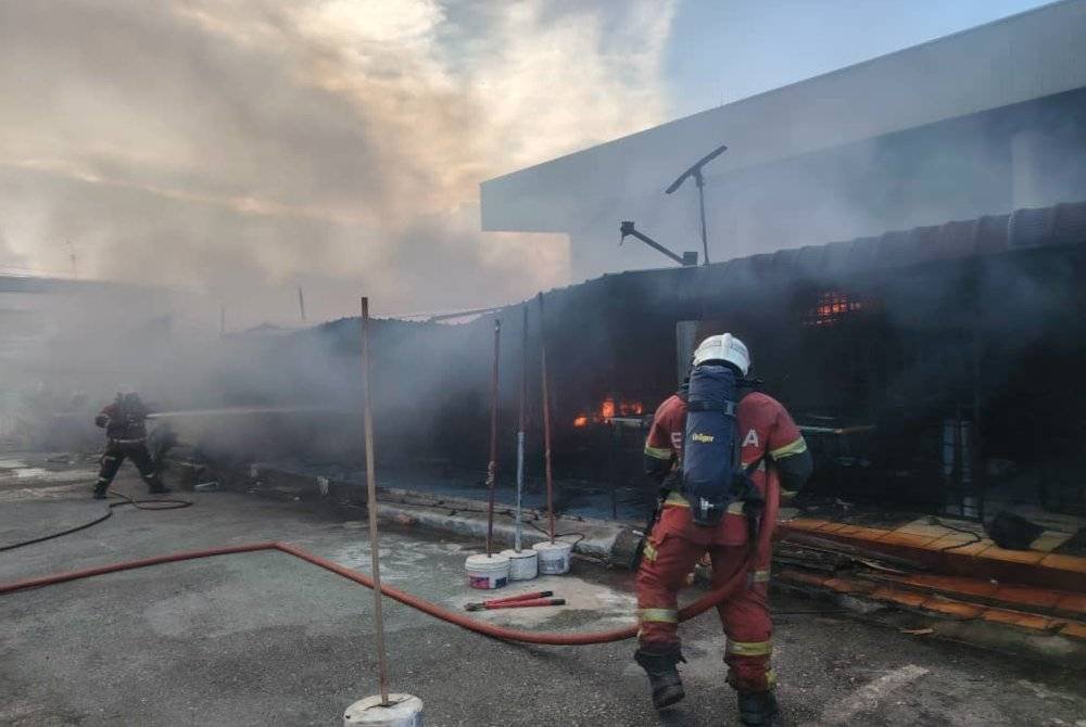Anggota bomba memadam kebakaran membabitkan lapan gerai makan di Taman Sri Puteri, Skudai. Foto JBPM