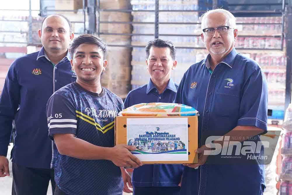 Pengerusi Lembaga Pertubuhan Peladang (LPP), Datuk Mahfuz Omar (kanan) menyerahkan kotak bantuan kepada wakil anggota negeri, Mohd Anhar Mohd Aman ketika Majlis Penyerahan Bantuan Bencana Agromakanan LPP di sini pada Isnin. FOTO SINAR HARIAN/ MOHD HALIM ABDUL WAHID