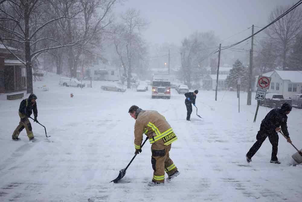 Beberapa anggota keselamatan membersihkan salji tebal yang menghalang lalu lintas.