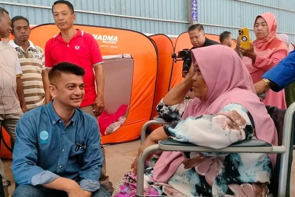 Muhammad Faiz (kiri) beramah mesra dengan mangsa kebakaran di Pusat Pemindahan Sementara Tanjung Dawai Kedah.