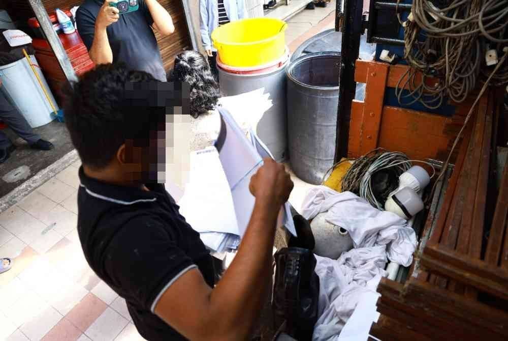 Seorang suspek menunjukkan dokumen semasa serbuan menerusi Op Loader Bahagian Perisikan SPRM di sekitar Melaka dan Lembah Klang pada Rabu.