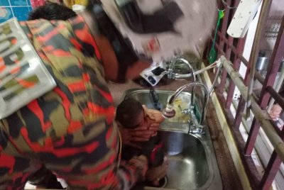 Anggota bomba mengeluarkan kaki bayi yang tersepit dalam lubang singki.