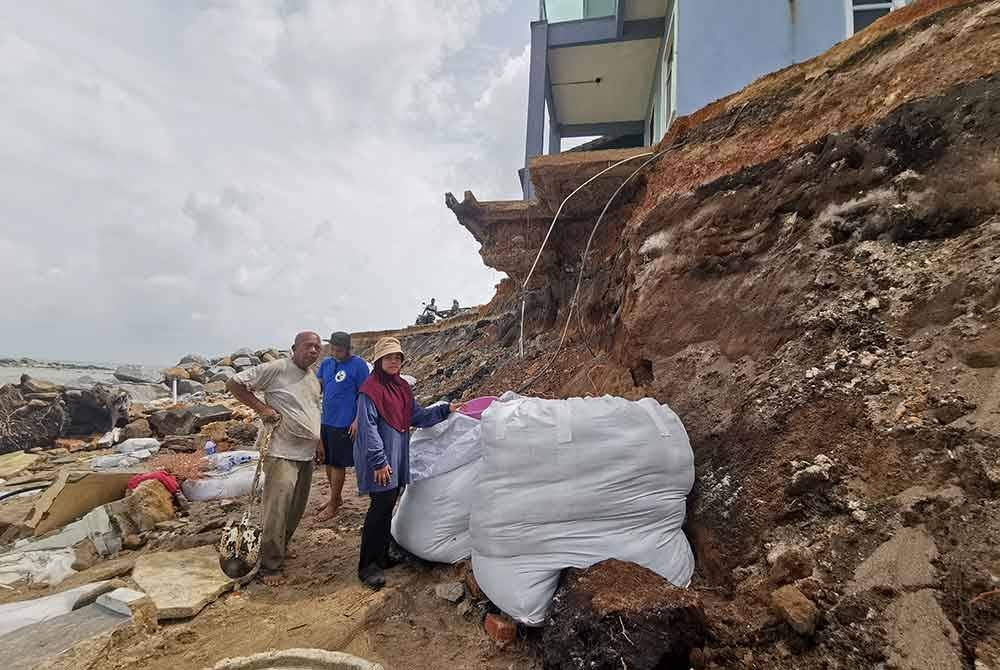 Mohd Yazid membina benteng pasir sebagai usaha menghalang hakisan di kawasan rumahnya daripada bertambah buruk.