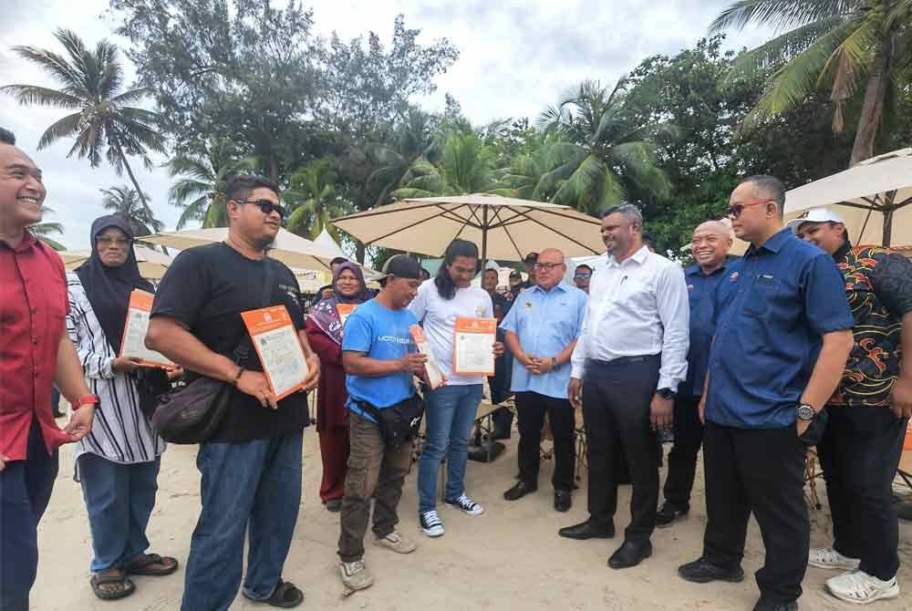 Arul Kumar (berbaju putih dari kanan) beramah mesra dengan pengusaha payung pantai