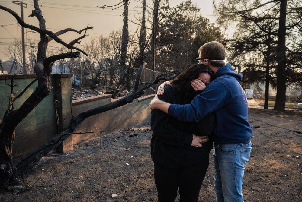 Seorang lelaki memeluk anak perempuannya ketika melihat kediaman mereka musnah terbakar di Altadena, California. AFP