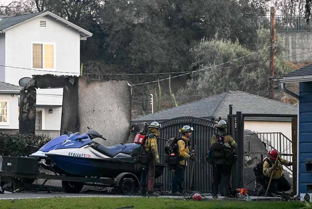 Anggota bomba berjalan di sekitar kawasan perumahan di Altadena, California yang terjejas akibat kebakaran hutan. Foto AFP