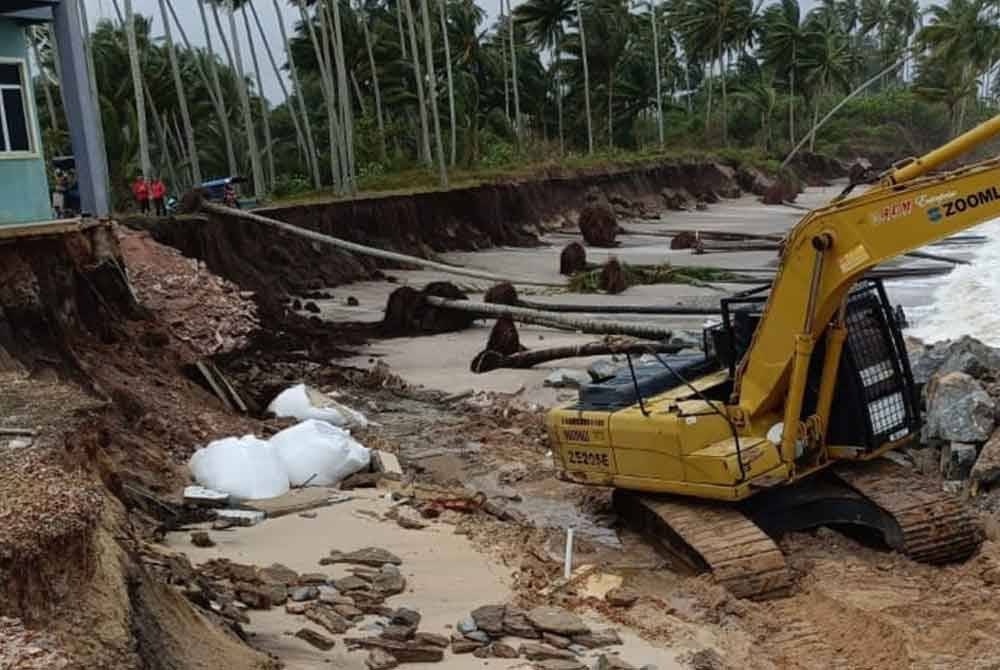 Penduduk dengan kerjasama pengusaha jentera pengorek (excavator) bergotong-royong membina benteng sementara di rumah berkenaan. Gambar: Ihsan keluarga