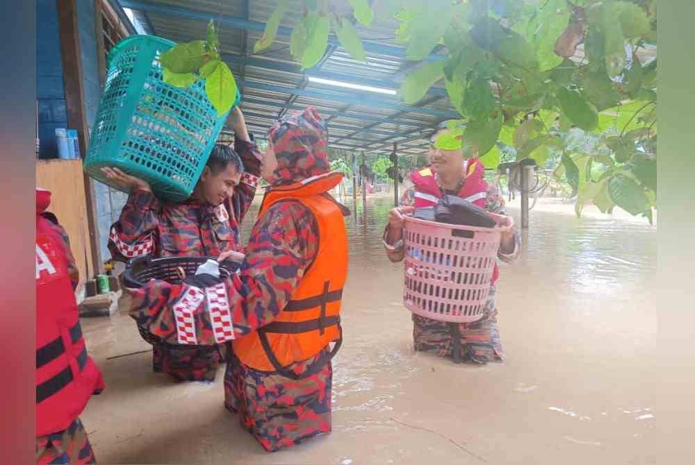 Anggota bomba membantu memindahkan mangsa banjir di Kampung Sri Gambut Pontian. - Foto JBPM