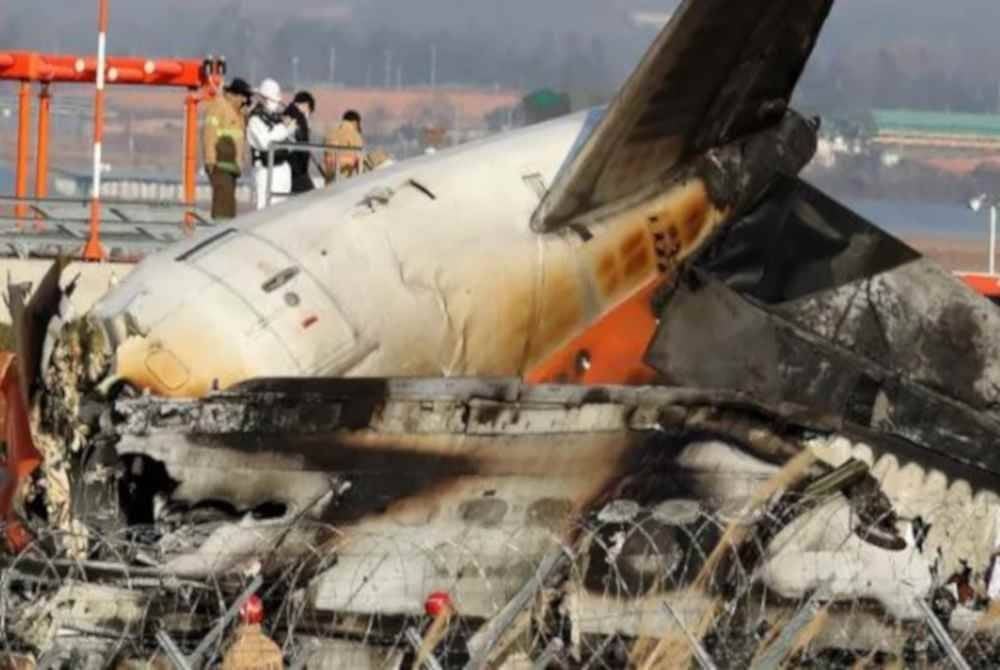 Dua kru yang terselamat duduk di bahagian ekor pesawat tersebut. Foto Agensi