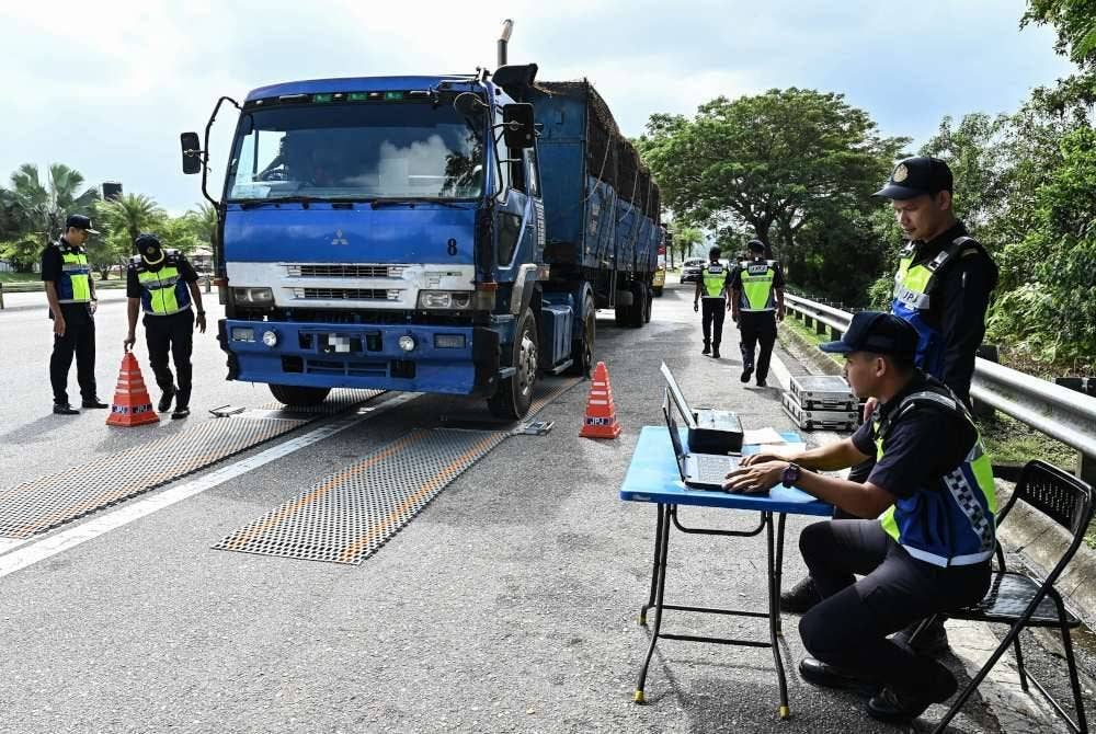 Anggota JPJ memeriksa berat muatan sebuah lori dalam Ops Gempur Teknikal di Plaza Tol Gemuruh. Foto Bernama
