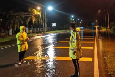 Anggota polis menjalankan pemantauan di lokasi air melintasi jalan di KM 4 Jalan Gembut, Tanjung Sedili Kota Tinggi. Foto IPD Kota Tinggi