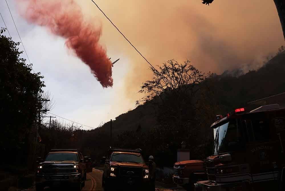 Sebuah kapal terbang memadam kebakaran bagi menghalang api daripada merebak lebih jauh di bukit Mandeville Canyon di Los Angeles, California. Foto Xinhua
