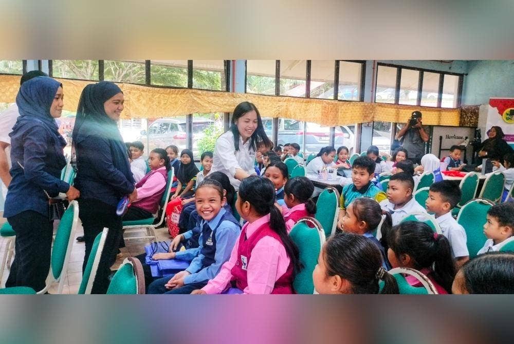 Nie Ching(kanan) menyantuni murid-murid di SK Bukit Rok.
