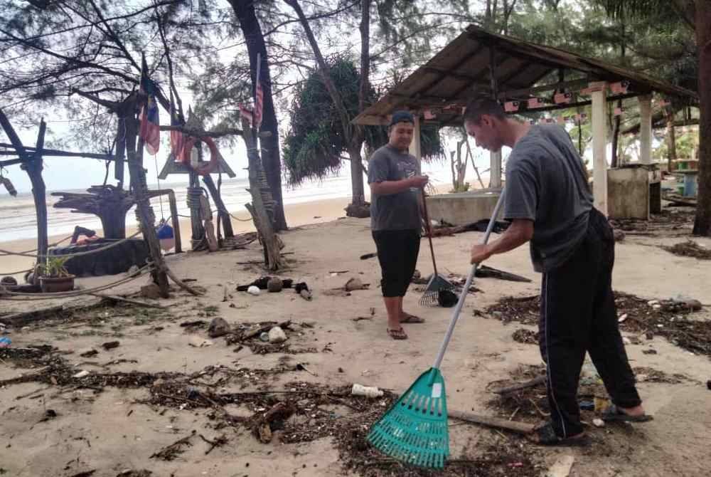 Mohd Azwan (kiri) membersihkan kawasan chalet miliknya.
