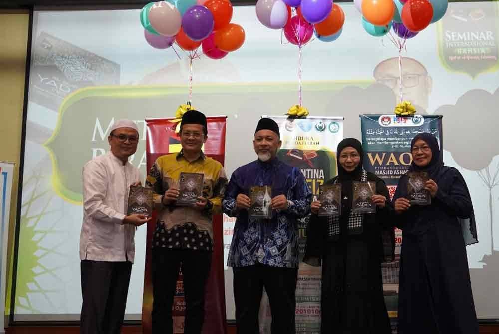 Ustaz Ma'mun (kiri) menyampaikan al-Quran Yadain kepada Ahli Lembaga Pemegang Amanah WUIF, Ahmad Yani Abd Manaf (dua dari kiri) sambil diperhatikan oleh Faudzinaim (tengah)