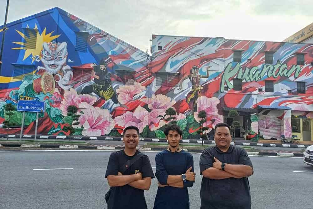 Mohd Ikmal (tengah) bersama Azri (kanan) dan Raja Mohd Faiz bergambar dengan berlatarbelakangkan mural di bandar raya Kuantan.