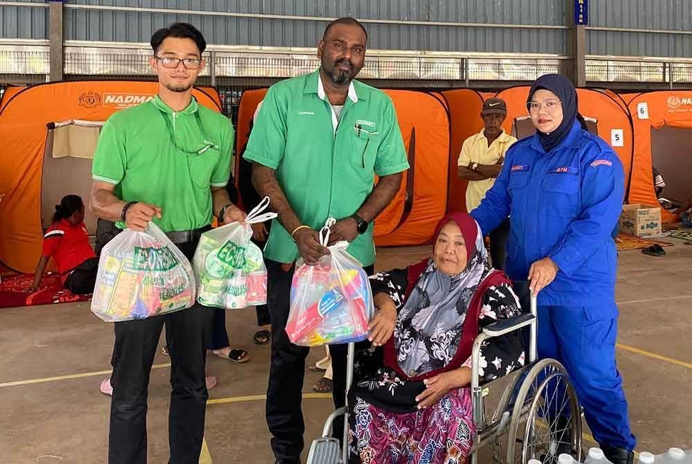 Kavikumar (dua kiri) menyampaikan sumbangan kepada salah seorang mangsa kebakaran di PPS SJKC Choong Cheng Tanjung Dawai.