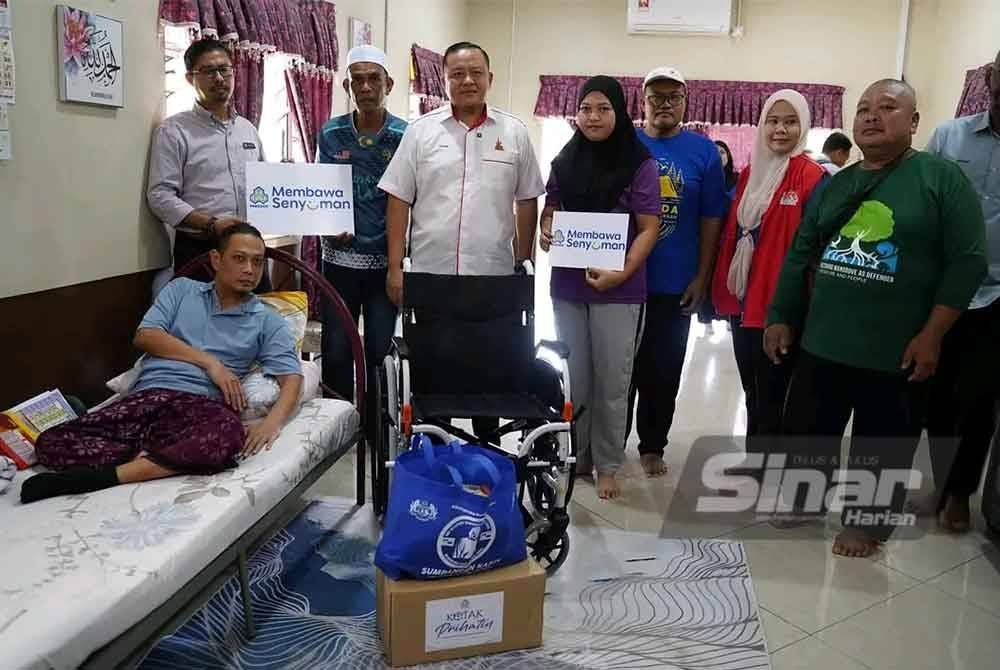 Rizam (tiga dari kiri) bersama wakil PERKESO dan kepimpinan masyarakat menziarahi Mohd Fairul di rumahnya di Kampung Sungai Air Tawar di sini pada Rabu.