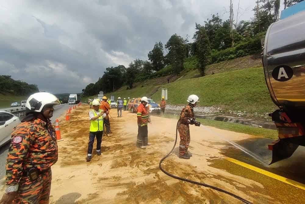 Pasukan bomba menjalankan operasi membersihkan kawasan tumpahan minyak sawit mentah selepas kenderaan membawa muatan itu bocor akibat kemalangan di Bidor. - Foto: Ihsan Bomba Perak