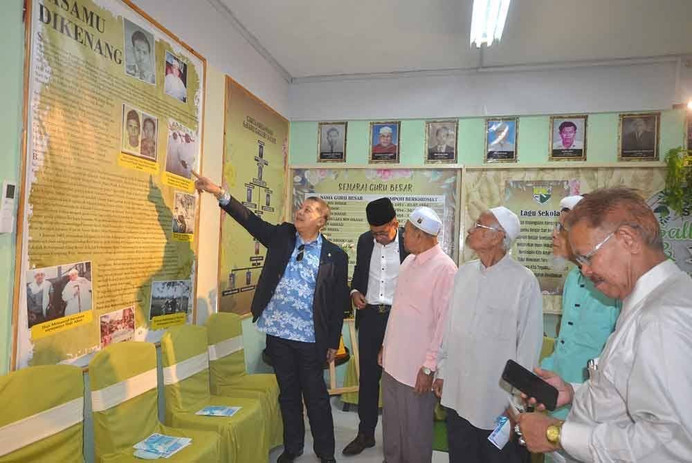 Wan Ahmad Najmuddin (kiri) menunjukkan gambar bapanya, yang merupakan antara pengasas sekolah berkenaan.