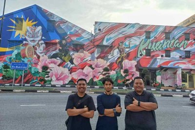 Mohd Ikmal (tengah) bersama Azri (kanan) dan Raja Mohd Faiz bergambar dengan berlatarbelakangkan mural di bandar raya Kuantan.