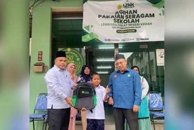 Salah seorang murid hadir menerima bantuan Skim Agihan Pakaian Seragam Daerah Kulim Bandar Baharu disampaikan Md Sharif (kiri).