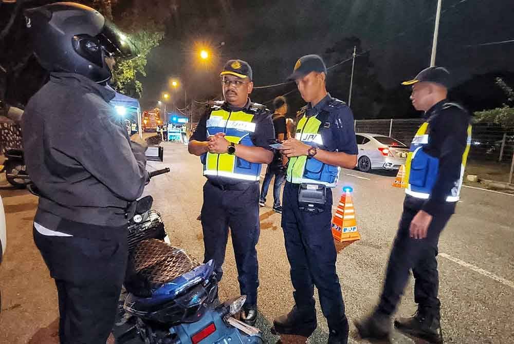 Muhammad Firdaus (dua, kiri) memeriksa LKM seorang penunggang motosikal.