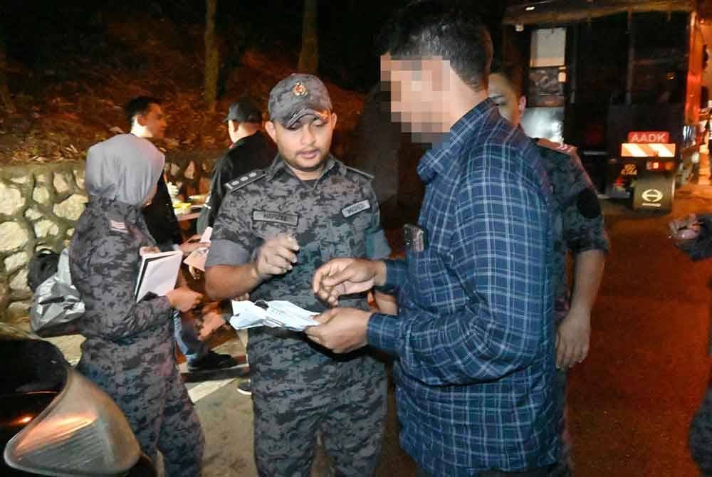 Mohd Hafizee (tengah) menahan seorang warga asing disyaki melakukan kesalahan tinggal lebih masa di negara ini.